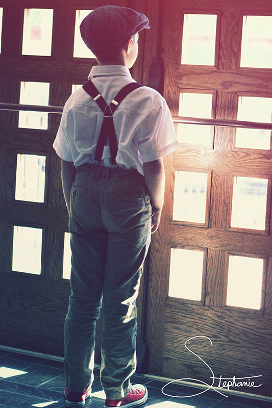 A boy looking out of a set of doors.