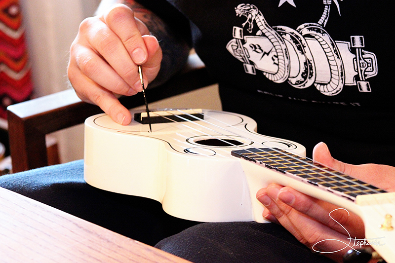 A photo of someone pinstriping a ukelale.