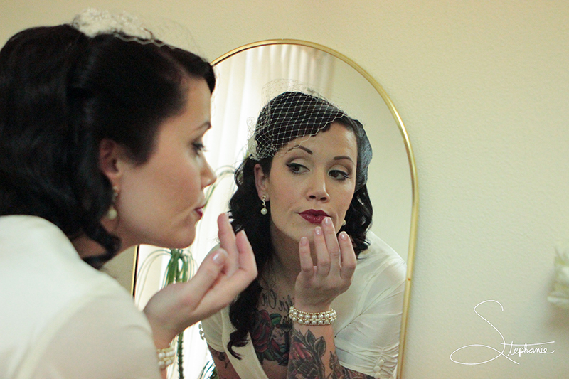 Bride checking her lipstick in a mirror.