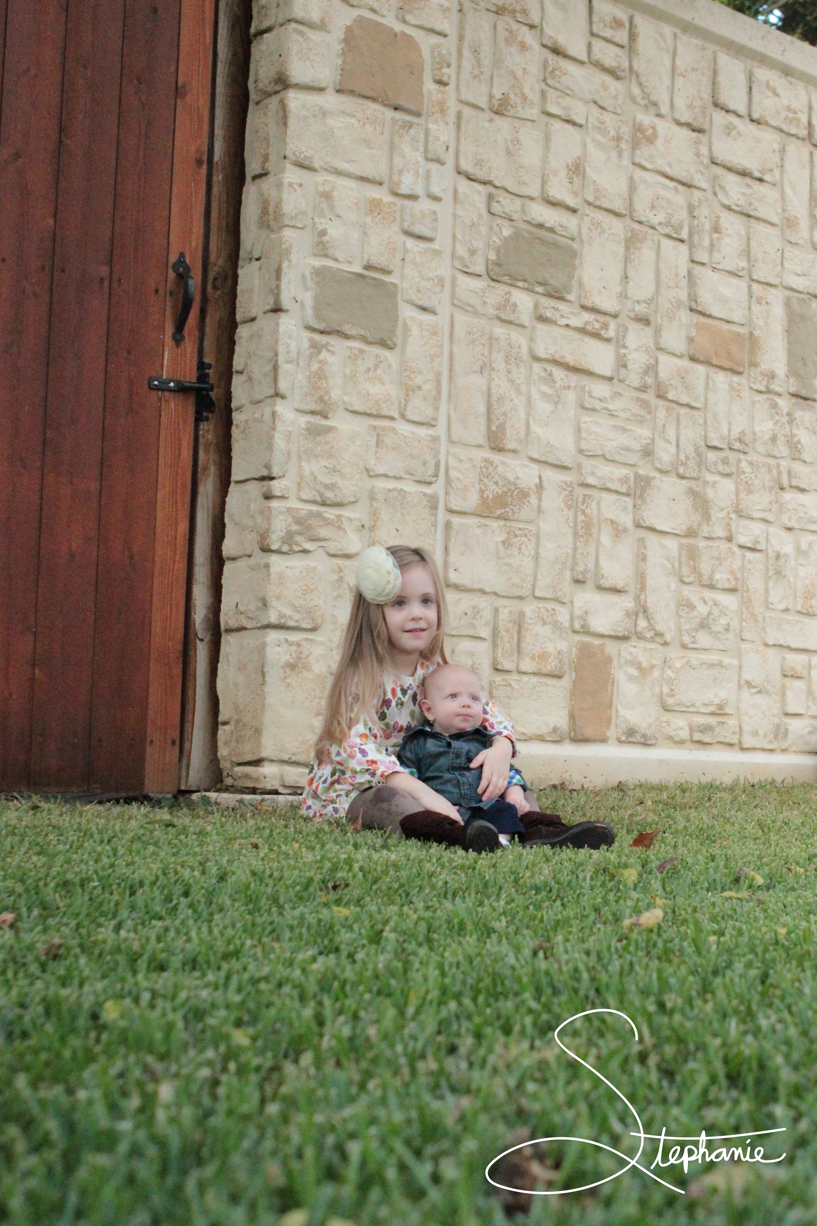 Photo of two small children sitting in the grass.