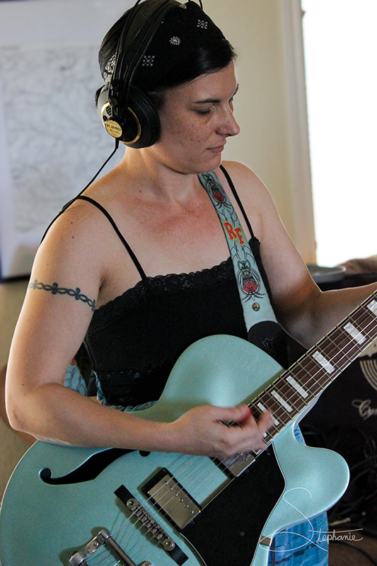 A woman playing guitar at a recording session.