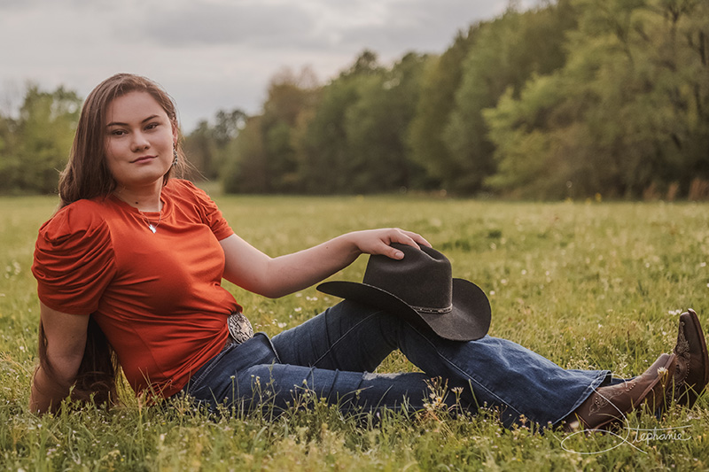 Photo of a cowgirl posing in a field.